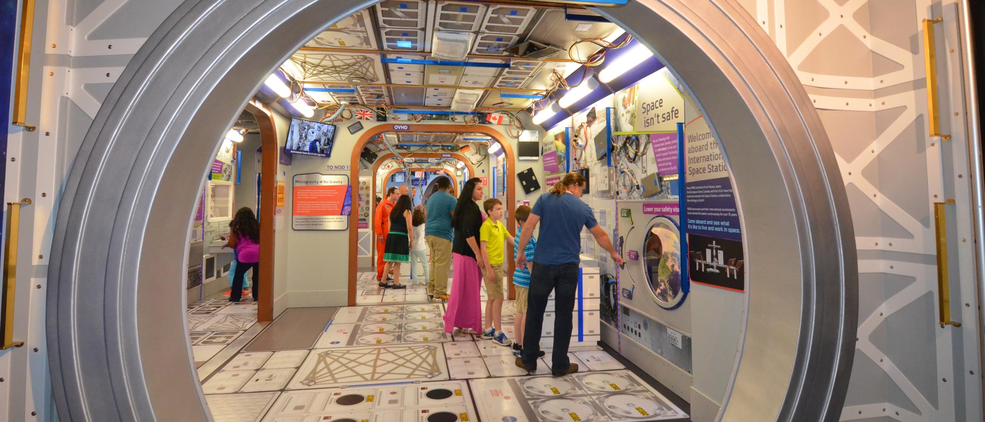 Families walking through the exhibit that's made to look like the inside of a space station.
