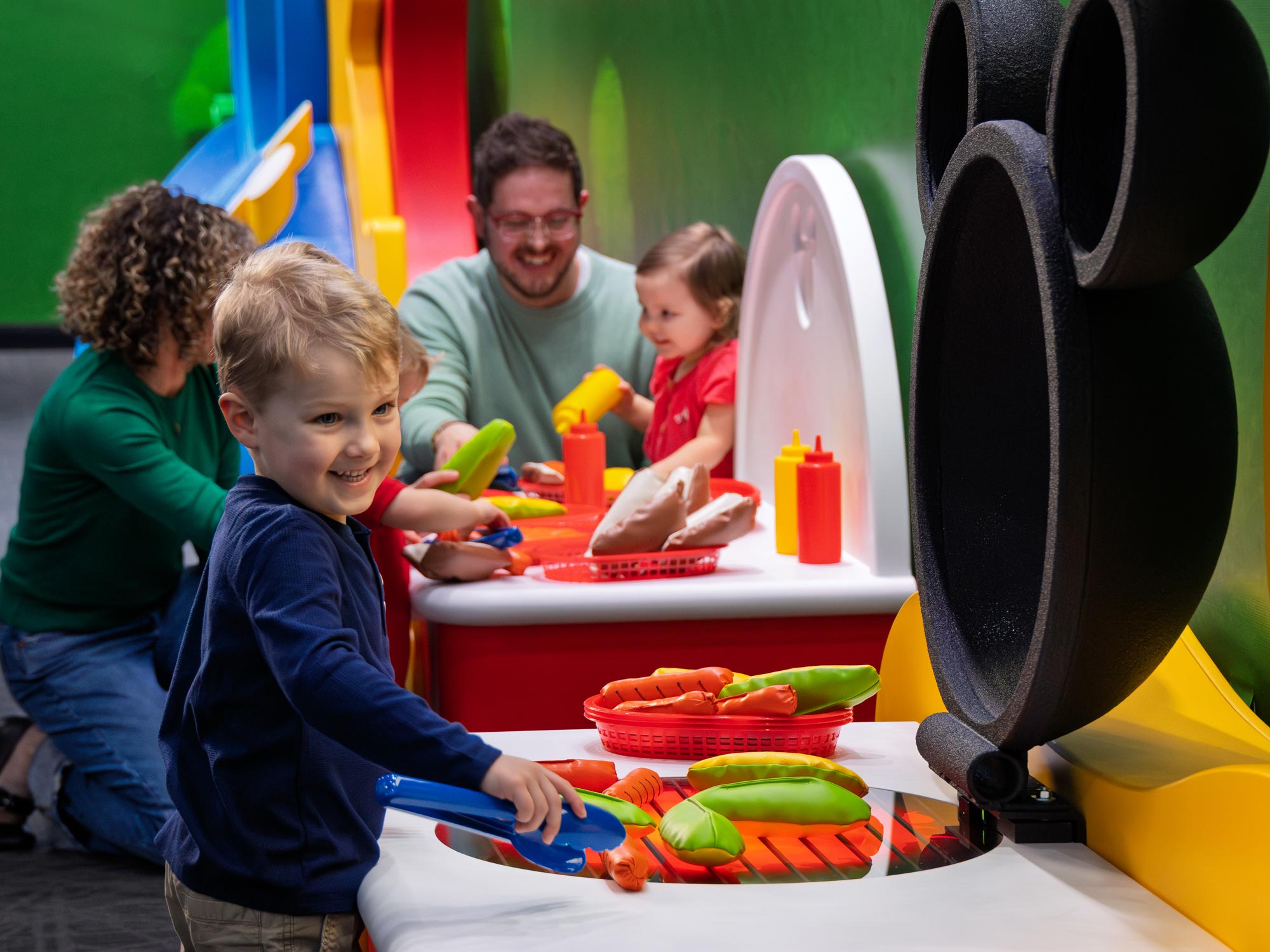 Child pretending to grill hot dogs inside the exhibit.
