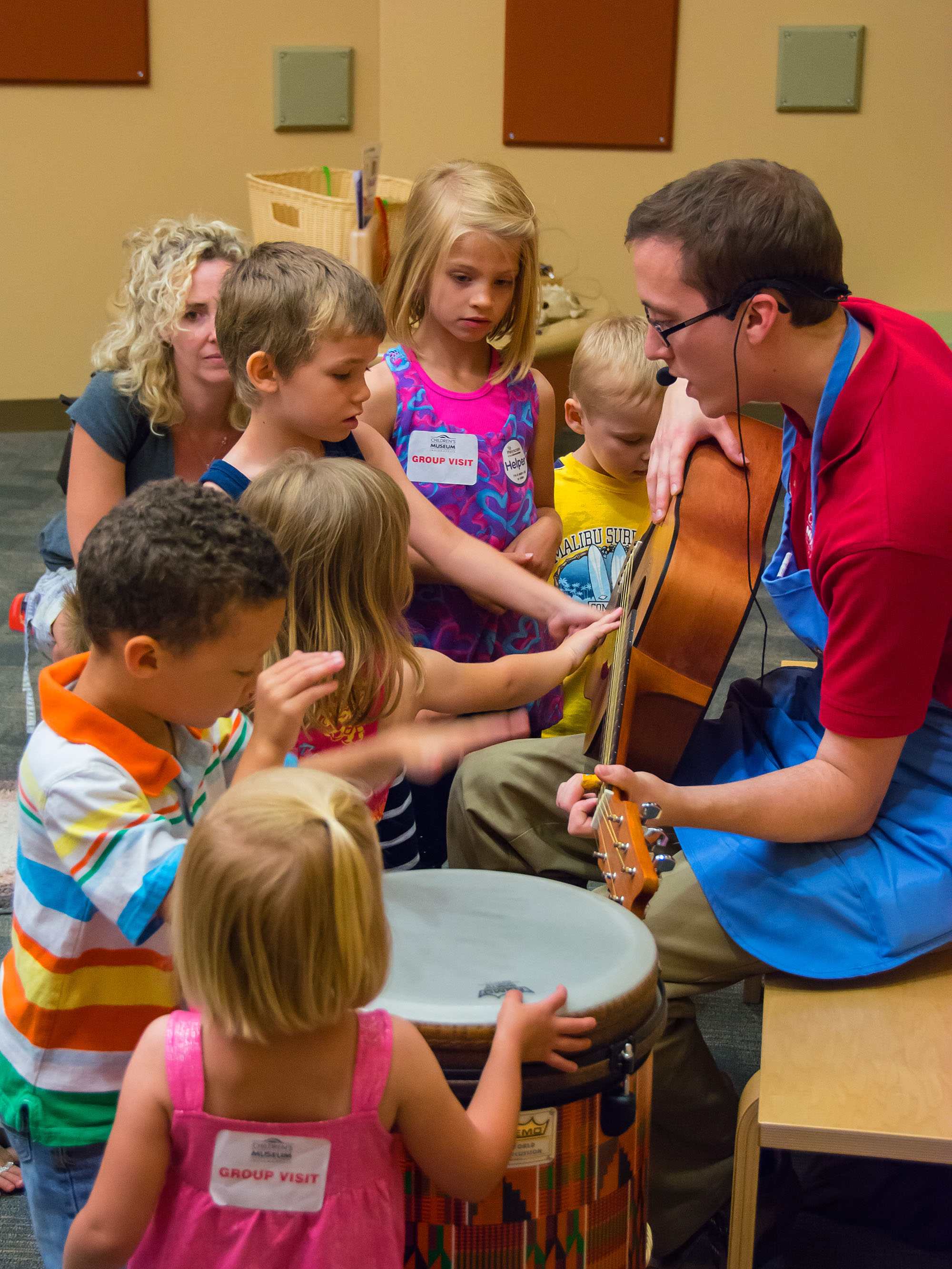 Children touching a guitar held by a grown-up staff member.
